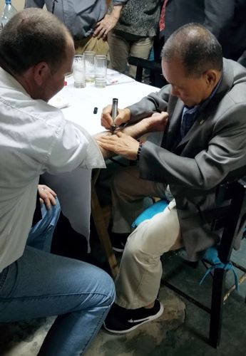 Grand Master Hwang writes on students forearm, creating a tattoo